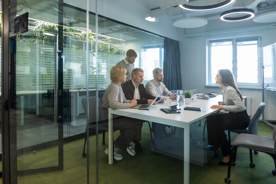 A view through a glass partition shows a modern, busy office interior. Job interview process is in office. Human resources, meeting and group of hiring candidates for vacancy