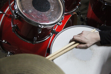 Fototapeta premium Drummer plays a rhythm on a red drum set in a music studio in the evening