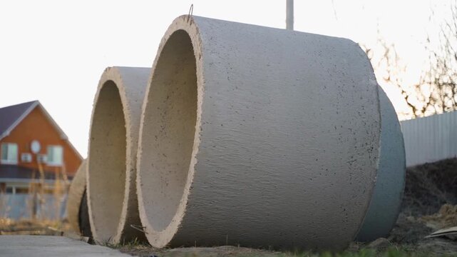 Concrete well rings stacked outdoors at sunset near rural house