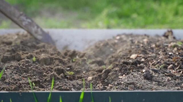 Slow motion of loosening garden bed soil with hoe and mixing with vermicompost