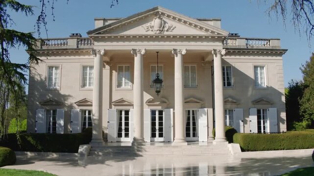 Moving camera approaching classical mansion facade on lawn, highlighting columns, pediment, lantern