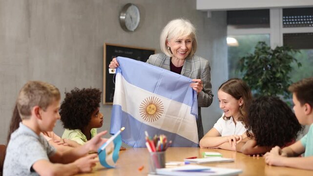 Female teacher showing argentinian flag to kids in geography class