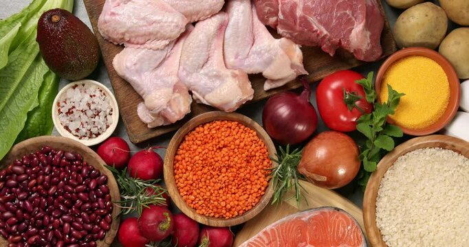Healthy products on a gray table. Close-up footage of fish, meat, chicken, onion, radish, lettuce, mint, avocado, tomatoes, potatoes, eggs, rice, beans, lentil pasta, corn porridge.