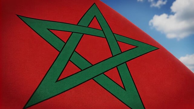 Waving flag bearing green interlaced star rippling at pole outdoors, wind picking up, revealing sky