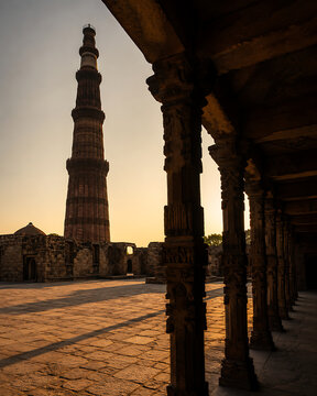 Photorealistic Qutub Minar dramatic shadow play on stone courtyard  minimalist composition