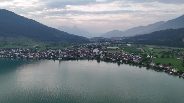Panorama flight over Lake Zug (Zugersee) with houses of village Arth and mountains in canton of Schwyz in Switzerland