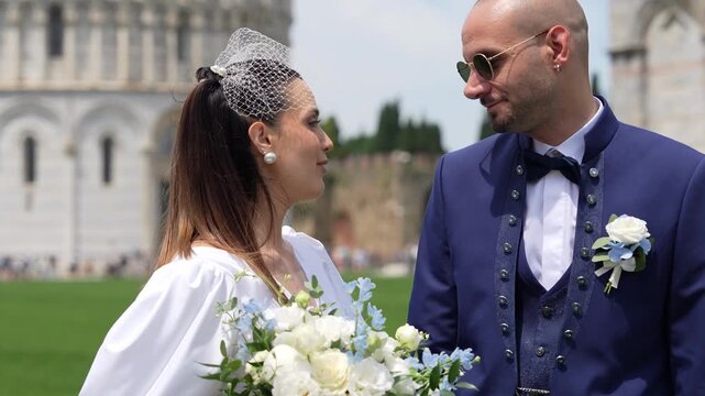 Bride and groom posing happily in the urban center surrounded by iconic monuments during wedding festivity in Pisa