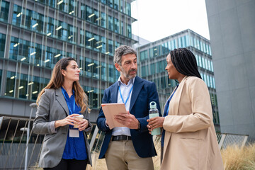 Fototapeta premium Diverse business team having outdoors discussion holding devices