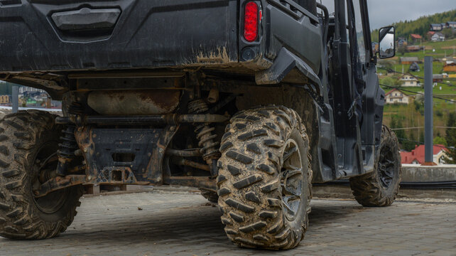 Rugged all-terrain vehicle with muddy tires parked on a paved surface