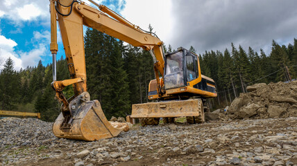 Yellow excavator working on a construction site in a forest clearing © shine.graphics