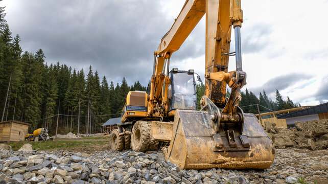 Heavy yellow excavator working on a construction site in a forest clearing