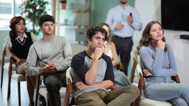 Young teacher stands in front of the students in the classroom and holds a remote control in the room and shows a presentation. Additional education and language learning