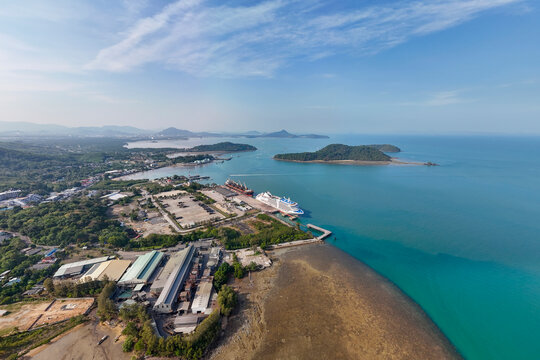 An aerial panorama of Phuket Deep Water Port showing a large cruise ship, cargo vessels, and industrial buildings along the coast