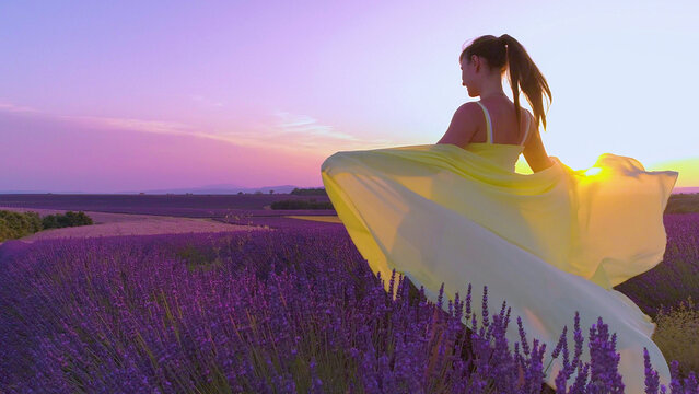 CLOSE UP: Girl in lavender field outstretches arms and lets scarf catch the wind