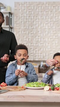 A diverse family is joyfully preparing a meal together in a bright, modern kitchen, engaging with ingredients and each other