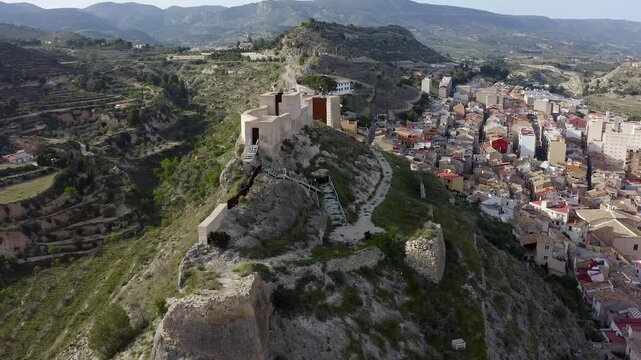 Aerial view of Jijona castle ruins in Alicante, Spain. Featuring accessible and visitable ruins within rugged mountainous landscape. 
