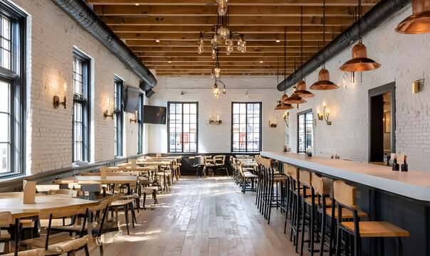 An interior shot, featuring a long bar and multiple dining tables, illuminated by overhead and wall lighting