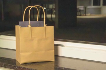 Brown paper bag on a windowsill in a dimly lit room during the evening © kinovo