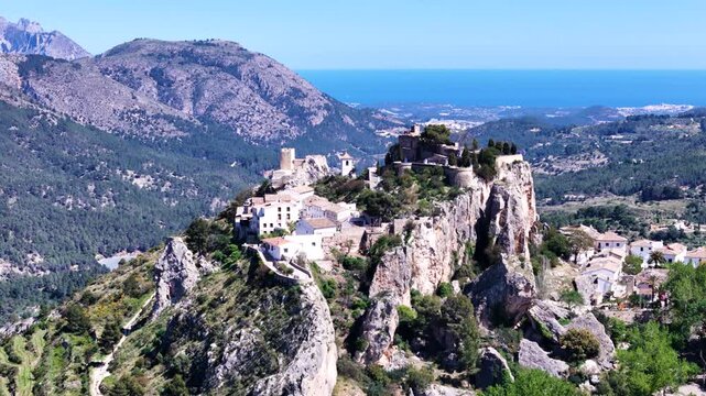 Breathtaking mountain range overlooking a vibrant blue sea and green forest landscape.