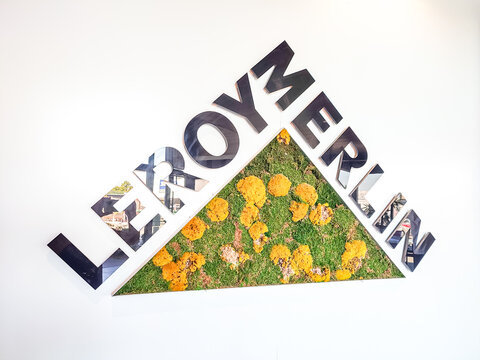 Le Mans, France - April 24, 2026: Leroy Merlin logo displayed on wall with vibrant green grass and yellow flowers in triangular design