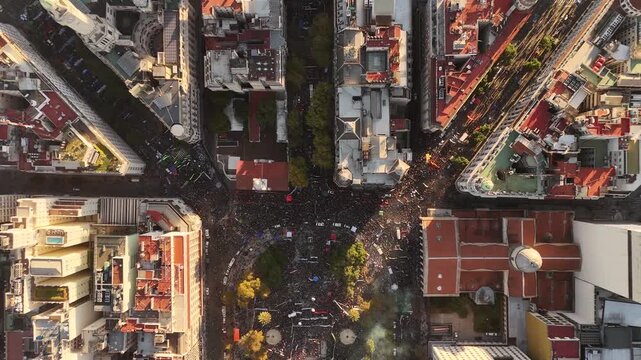 Drone descending from high altitude towards massive crowd at university protest in Plaza de Mayo, Buenos Aires, Argentina. Aerial top-down view