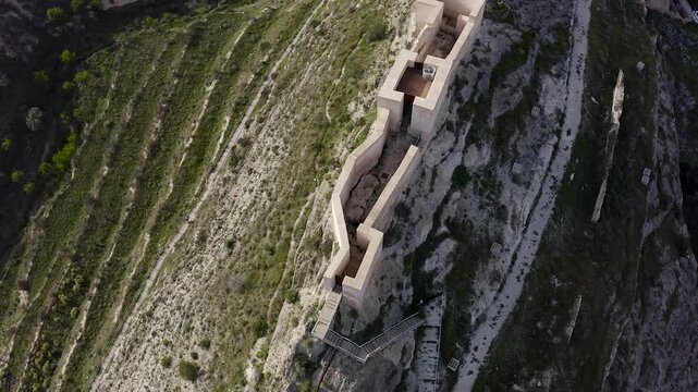 Aerial view of Jijona castle ruins in Alicante, Spain. Featuring accessible and visitable ruins within rugged mountainous landscape. 