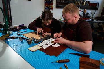 Fototapeta premium Collaborative art workshop with leatherworkers tracing on leather.