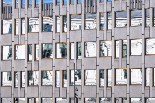 Grid facade of a building shows glass windows and reflection across urban office architecture, turning rectangular panels into precise detail