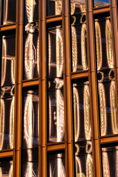 Golden reflection runs through a metal facade where glass windows turn architecture into an urban office pattern with compressed vertical detail