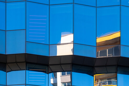 Saturated blue glass covers a building facade where windows and reflection make urban office architecture read as bold geometric detail