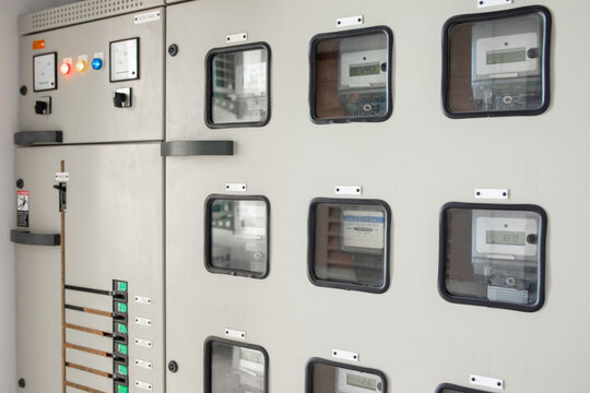 Closeup of industrial electrical switchgear cabinet with analog meters digital displays and multiple circuit breaker drawer units in building in Asia