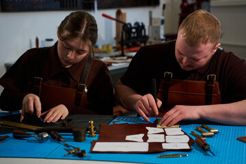 Fototapeta premium Leatherworkers using punches and creasers in a collaborative workshop.