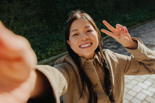 Smiling woman taking a selfie and flashing peace sign