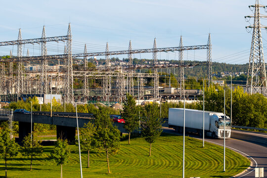 Power grid infrastructure stretches beyond a green road in Oslo Norway, linking urban transport movement with industrial utility detail