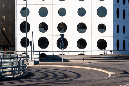Circular windows mark a graphic facade in Stockholm Sweden, as architecture, urban road curves and transport shadows form a bold pattern