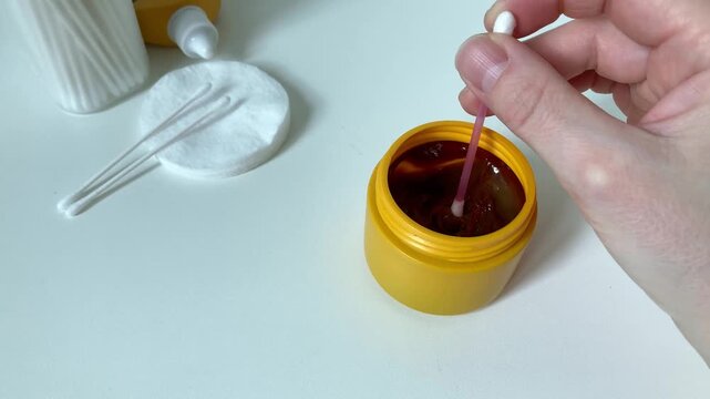 Woman puts iodine ointment on cotton swab. Treating an infected wound and preventing further inflammation. Using of iodine ointment helps to fight bacteria, clean wound and accelerate healing process