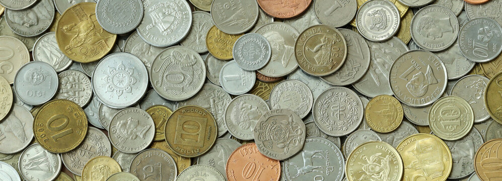 Top view of assorted coins, numerous world currencies together. Shiny metal pieces in mound