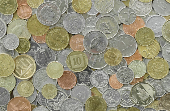 Top view of assorted coins, numerous world currencies together. Shiny metal pieces in mound
