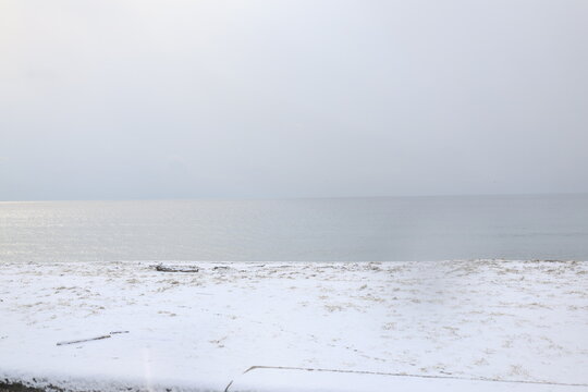 曇りの日の雪が積もった砂浜と海