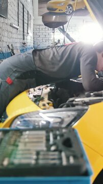 A mechanic checks the electrical in the hood of the car- repairing in engine compartment