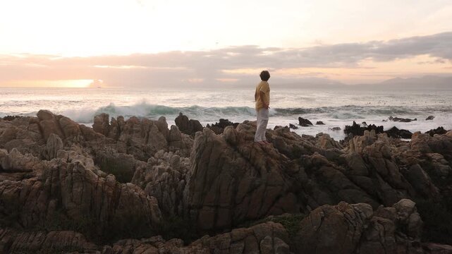 young boy exploring rocky coastline of DeKelders, Gansbaai, South Africa