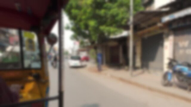 Blurry view of daily vehicle traffic and cityscape on Pathergatti Road from passenger seat of a rickshaw in Hyderabad, India. Real time bokeh motion video for background.