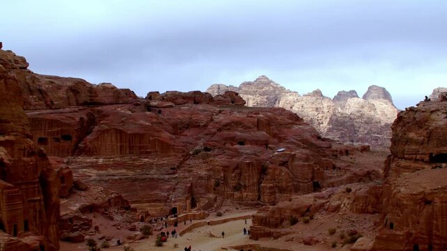 Daytime timelapse of the ancient Nabataean city of Petra, Jordan. Red sandstone mountains and archaeological ruins under a moving sky. UNESCO World Heritage site and iconic travel destination