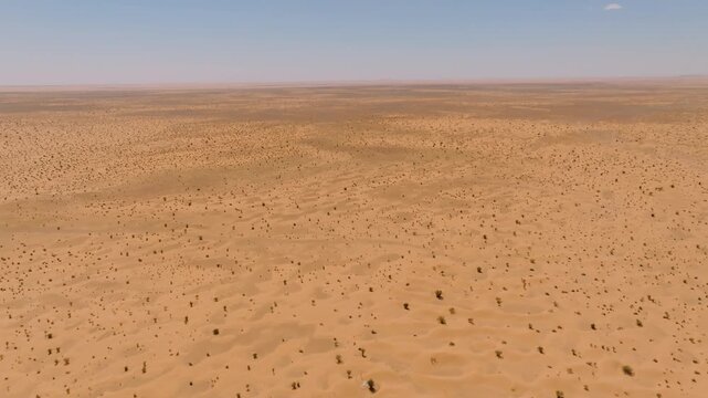 Aerial view of the flat, rocky "reg" desert plains in Tunisia, showing the transition between sandy dunes and the vast, barren horizons of the North African wilderness