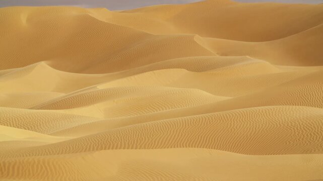 Close-up drone tracking shot over the crests of Saharan dunes in Tunisia, highlighting the intricate geometric patterns created by wind and sand