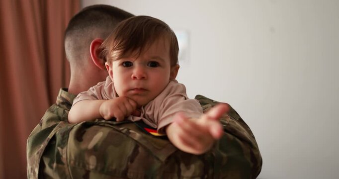 German male soldier in military uniform hugs his little son at home - Emotional military happy homecoming concept - UGC content