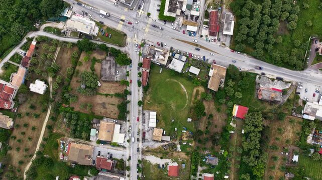Top down aerial view of the main crossroads intersection in Roda village, North Corfu, showing traffic, cars, and pools.