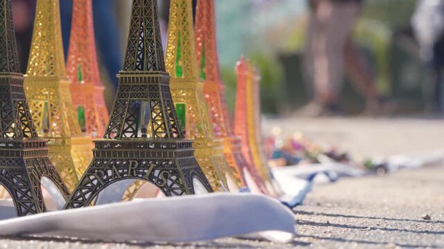 Eiffel Tower Mini Souvenirs In Paris Street Scene With Tourists Walking By, Close Up Replicas With Busy City Background &mdash; natural light shot