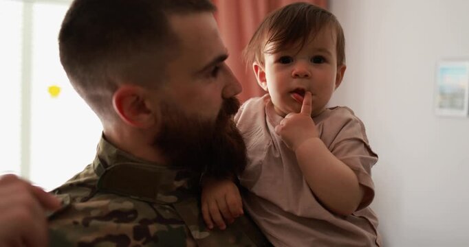 Male soldier in military uniform hugs his little son at home - Emotional and happy homecoming concept - UGC content