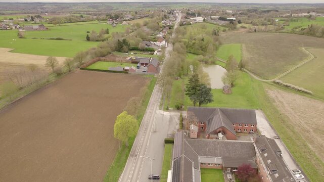 Aerial View of Rural Road Traffic Through European Countryside Village, Farmland and Agricultural Landscape in Wallonia